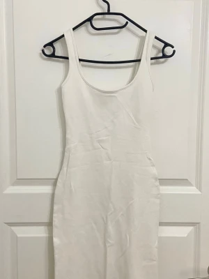 Vit långklänning  - Enkel och stilren vit klänning med breda axelband och rundad urringning. Klänningen har en figurnära passform. Perfekt för sommardagar eller när du vill ha en clean look. Aldrig använd, säljer eftersom den inte kom till användning 💕