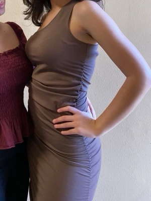 Brun oneshoulder klänning - Säljer en snygg bodycon midiklänning i brun från Bikbok. I storlek S! Klänningen var väck hela vägen på varsin sida!