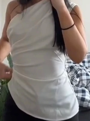 Vit oneshoulder topp - Snygg vit topp med oneshoulder-design och figurnära passform. Tyget är slätt och har en lätt glansig finish som ger en stilren look. Perfekt att matcha med jeans eller kjol för en trendig outfit.