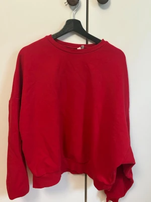 Röd sweatshirt från Nelly - En enkel och snygg röd sweatshirt från Nelly i storlek L. Tröjan har rund halsringning, långa ärmar och ribbade muddar vid ärmslut och nederkant. Tillverkad i mjukt bomullsmaterial som är skönt att bära. Perfekt för en avslappnad och trendig look.
