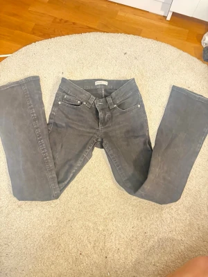 Svarta utsvängda  jeans från Gina Tricot - Säljer ett par svarta jeans från Gina  med utsnängd  passform och klassisk femficksdesign. Jeansen har bälteshällor, dragkedjegylf och silverfärgade nitar. Materialet är kraftig denim i bomull. Perfekta för en avslappnad och stilren look.