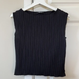 Svart ribbad ärmlös topp - Säljer en svart ärmlös topp från Gina Tricot med ribbad struktur och rund halsringning. Har använt en gång. Stretchigt material🤍