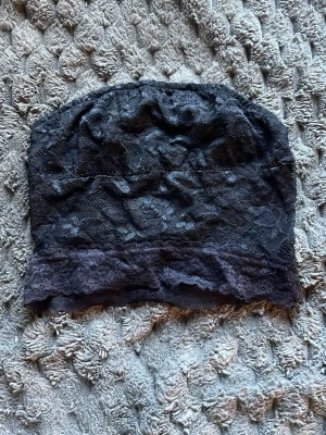 Svart spets bandeau topp - Säljer en svart bandeau topp i mjuk spets med blommigt mönster. Toppen är axelbandslös och har en bred spetskant nedtill för extra komfort och stil. Perfekt att bära under toppar med bar rygg eller axlar.