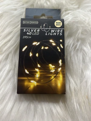 Silver LED ljusslinga 195 cm varmvit - Säljer en silverfärgad LED ljusslinga med 40 små lampor och varmvit sken. Slingan är 195 cm lång och batteridriven, perfekt för att skapa mysig stämning i rummet eller till dekoration. Levereras i originalförpackning. Oöppnad