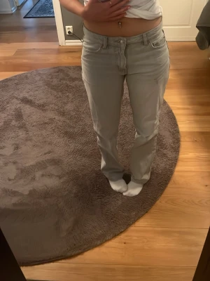 Ljusgrå raka jeans - Säljer ett par ljusgrå jeans med rak passform och klassisk femficksdesign. Jeansen har normal midja och stängs med dragkedja och knapp. Perfekta till en avslappnad stil och passar till det mesta. Materialet är denim i bomull. De har en blyertsflöck som ej går bort i tvätten 