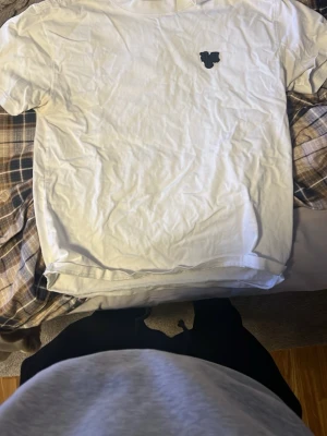 Vit t-shirt med svart logga från demont   - Vit t-shirt med en liten svart logga på bröstet. Klassisk rund hals och korta ärmar. Enkel och stilren design som passar till det mesta. Tillverkad i mjukt material för skön känsla.