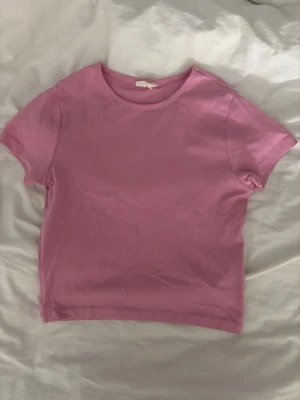 Croppad t-shirt - Rosa tight T-shirt från Gina, stl L men funkar för det flest storlekar beroende på hur man vill att den ska sitta. Kort och tight passform.
