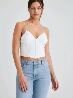 Vit korsettopp - Trendig vit korsettopp med tunna axelband och snygga rynkade detaljer på sidorna. Toppen har en croppad passform och markerad midja som ger en modern siluett. Perfekt att styla med jeans eller kjol för en cool look.