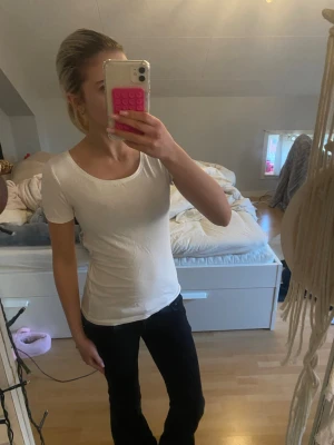 Vit tight t-shirt med knytning där bak - Säljer en egensydd vit, tight t-shirt med korta ärmar och rund halsringning. T-shirten har ett snyggt knytband i ryggen som ger en unik detalj. Perfekt till jeans eller kjol för en clean och enkel look. Eftersom den är handgjord från en långärmad tröja till en Tshirt med knytning så kan den ha några trådar osv.