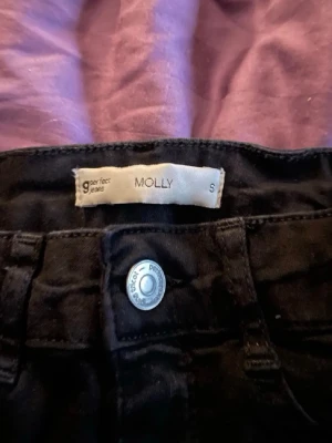 Svarta Molly jeans från Gina Tricot - Säljer ett par svarta Molly jeans från Gina Tricot. Jeansen har hög midja, skinny fit och klassisk femficksmodell. Stretchigt material som sitter tajt och bekvämt. Perfekta till alla dina outfits!