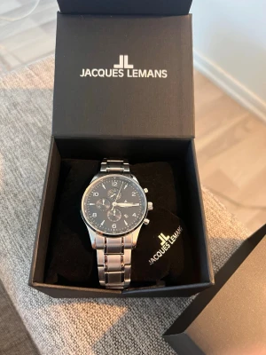 Jacques Lemans London  - Stilren klocka från Jacques Lemans med silverfärgad länk i metall och marinblå urtavla. Klockan har tre mindre urtavlor, datumvisning och tydliga siffror. Perfekt accessoar för dig som gillar klassisk och manlig stil. (44mm med alla linkar på) Det finns 2 extra länkar som är borttagna men kommer med på köpet. Dm för mer information eller intresse. (Helt ny och oanvänd) kvitto finns !!! 