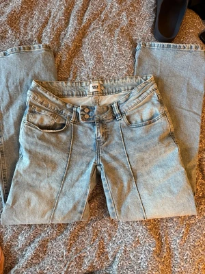 Ljusblå bootcut jeans från lager 157 - Säljer ett par ljusblå bootcut jeans från lager 157 med klassisk femficksmodell och markerad söm framtill. Jeansen har låg midja och är tillverkade i mjuk denim med lite stretch för skön passform. Perfekta till sneakers eller boots.