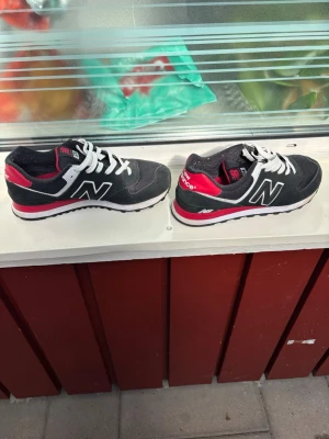 Svarta New Balance sneakers - Snygga svarta New Balance sneakers med vita och röda detaljer. Riktig feta skor skulle jag säga och väldigt bra skick fortfarande och jag har bara använt de 3 gånger och vill gärna sälja de för att tjäna lite pengar. Vid snabbköp kan man diskutera priset men annars är det också fritt fram att komma och ge prisförslag🫱🏾‍🫲🏼