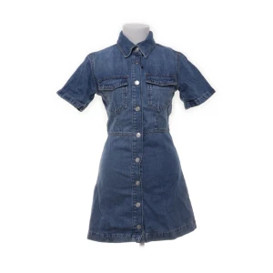 Jeansklänning med knappar från Zara - Säljer en snygg jeansklänning från Zara i klassisk blå denim. Klänningen har korta ärmar, krage, knäppning framtill och två bröstfickor. Perfekt för dig som gillar en tidlös och cool stil. Storlek S. Använd 1 gång. Nypris 550kr. 