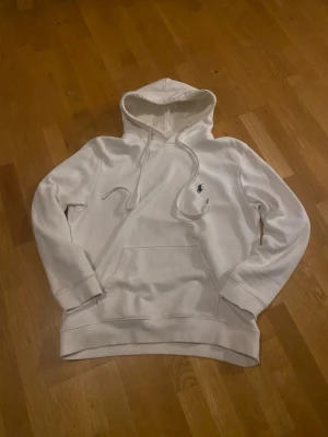 Vit  Ralph Lauren hoodie - Vit hoodie från Polo Ralph Lauren med klassiska broderade loggan på bröstet. Stilren och tidlös modell som passar till allt.  • Färg: Vit • Skick: mycket Bra skick (använd lite men väl omhändertagen) • Passform: Normal • Material: Mjuk och bekväm bomullsblandning Perfekt för både vardag och chill outfits 🤍 Säljs då den inte används längre.  Skicka meddelande vid frågor eller för fler bilder!
