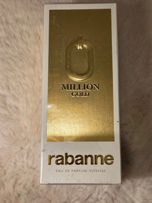 Rabanne 1 Million Gold EdP 100ml - Rabanne 1 Million Gold Eau de Parfum Intense är en lyxig parfym i en elegant vit och guld förpackning. Flaskan rymmer 100 ml och har en exklusiv design med guldfärgade detaljer och tydlig logotyp. Perfekt för dig som gillar intensiva och unika dofter.