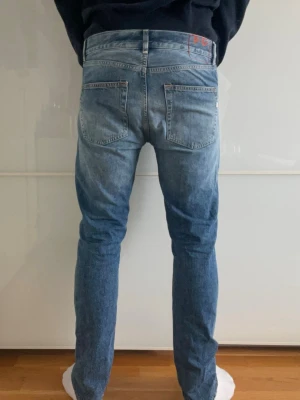 Dondup jeans - Säljer ett par blå dondup jeans med klassisk femficksdesign och lätt slitna detaljer. Jeansen har normal midja och raka ben, perfekta för en avslappnad och trendig look. Tillverkade i mjukt denimtyg som ger skön passform.