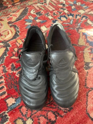 Svarta Adidas Copa fotbollsskor - Säljer ett par klassiska svarta Adidas Copa fotbollsskor i läder med snörning och låg profil. Skorna har diskret Adidas-logga på plösen och tre svarta ränder på sidan. Perfekta för dig som gillar tidlös stil på planen. Priset går att acceptera vid snabb affär. Bara att höra av sig i chatten!!!