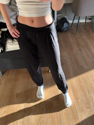 Svarta mjukisbyxor med hög midja - Säljer ett par svarta mjukisbyxor med hög midja och avslappnad passform. Byxorna har resår i midjan och är gjorda i ett mjukt, stretchigt material som är perfekt för chill dagar. Passar dig som gillar en enkel och bekväm stil. Storlek S