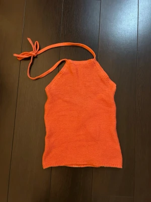 somrig halterneck ny med prislapp - Säljer en korall halterneck topp med knyt i nacken. Toppen är gjord av certifierad ekologisk bomull och har en enkel, clean design utan mönster. Perfekt för dig som gillar färg och vill ha något bekvämt och snyggt till sommaren.
