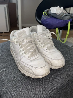 Vita Nike Air Max 90 sneakers - Säljer ett par klassiska vita Nike Air Max 90 sneakers med chunky sula och ikonisk Air-dämpning. Skorna har en stilren design i vitt läder och mesh, med vita snören och detaljer. Perfekta för dig som gillar streetwear och sportig stil. SMUTSIGA MEN I PRINCIP SOM NYA EFTER TVÄTT