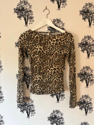 Leopardmönstrad långärmad topp🐆🤎 - Snygg långärmad topp med leopardmönster i bruna och beige toner. Figurnära passform och rund halsringning. Perfekt för dig som vill sticka ut med ett djuriskt print. Materialet känns mjukt och stretchigt, vilket gör toppen bekväm att bära.