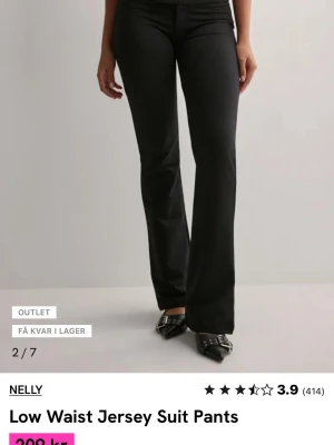 Svarta low waist kostymbyxor Nelly - Snygga svarta kostymbyxor från Nelly med låg midja och utsvängda ben. Tillverkade i mjukt jerseytyg som ger en bekväm och följsam passform. Perfekta för en trendig och avslappnad look. Ett litet litet hål på högra benet längst ner, skriv till mig för bild 