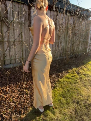 Gul satinklänning - Ljusgul satinklänning med öppen rygg samt liten dragkedja och band baktill från In the Style som ej är använd, perfekt till balen 💗