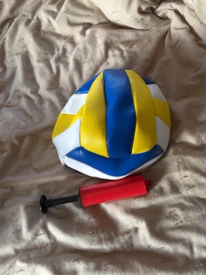 Volleyboll med pump blå/gul/vit - Volleyboll i blått, gult och vitt med klassiskt mönster. Tillbehör: röd och svart bollpump. Perfekt för träning eller spontanspel på stranden eller i parken. Tillverkad i syntetmaterial.