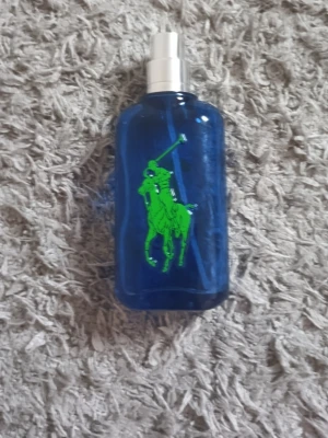 Ralph Lauren Big Pony 1 Herrparfym - En snygg herrparfym från Ralph Lauren i serien Big Pony. Flaskan är blå med en stor grön polospelare på framsidan och en gul etta på baksidan. Flaskan har en modern, sportig design och är tillverkad i glas med silverfärgad spraykork.
