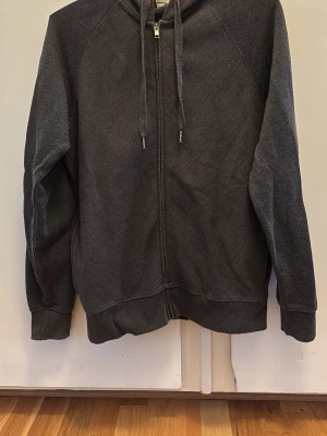 Mörkgrå zip hoodie från Tezenis - Mörkgrå hoodie från Tezenis med dragkedja framtill och justerbar huva med snören. Storlek S.