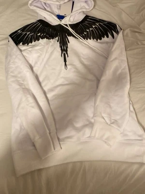 Marcelo burlon  - Säljer en vit hoodie från Marcelo Burlon med ett svart vingmönster 