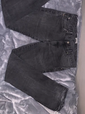 Svarta flared jeans - Säljer ett par svarta flared jeans. Jeansen har klassisk femficksmodell och knappgylf. Materialet är denim i bomull och de har en avslappnad passform. Perfekta för en cool och avslappnad stil.
