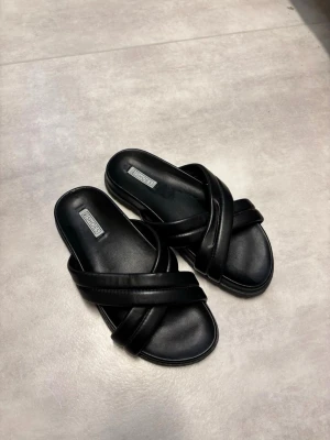 Svarta slip-in sandaler från Nelly - Stilrena svarta sandaler från Nelly.  Endast använda fåttal ggr. Storlek 38.