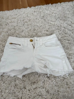 Vita fransiga shorts med dragkedjor - Säljer ett par vita shorts från Cobra med blixtlås detaljer! Köpte secondhand förra året men det var för små för mig!