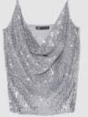 Glittrig silver topp med drapering - Snygg glittrig silver topp med draperad front och smala axelband. Perfekt för dig som vill sticka ut och glänsa. Toppen har en croppad passform och är tillverkad i ett syntetmaterial som ger extra skimmer.