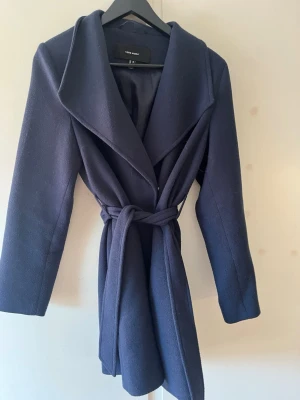 Kappa med knyt och knappar  - En lite längre marinblå kappa från vero Moda. Använd en höst men fortfarande i fint skick. 