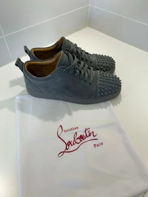 Grå spikesneakers från Louboutin - Snygga grå sneakers i mocka från Christian Louboutin. Storlek 43! Mycket bra skick, som du kan se är skorna inte alls använda mycket. Kan gå ner i en del i pris vid en smidig och snabb affär. 