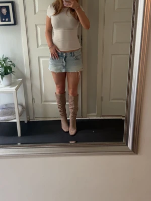 Beige knähöga  - Säljer ett par snygga knähöga stövlar i beige mocka med klack. Stövlarna har en smal passform och rundad tå, perfekta till både jeans och kjol. De är stilrena och trendiga, passar till många olika outfits.