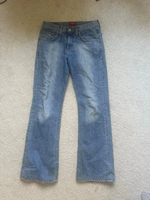 Ljusblå bootcut jeans från Big Star - Säljer ett par ljusblå jeans från Big Star med klassisk femficksmodell och bootcut passform. Jeansen har en avslappnad look med lätt slitningar och är tillverkade i bomullsdenim. Perfekta för dig som gillar retrostil och bekväma jeans.