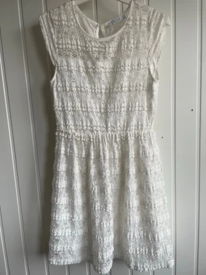 Vit spetsklänning med volangdetaljer - Jätte fin vit spets klänning från vila som köptes för flera år sedan. Knappt använd 