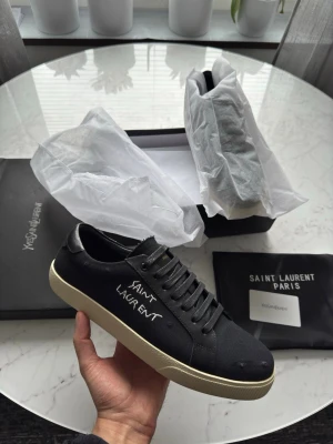 Svarta ysl sneakers oanvända  - Snygga svarta sneakers från Saint Laurent med vit logga broderad på sidan. Finns att hämta i Götenborg eller skickas. Helt nya oanvända Storlek 44. 