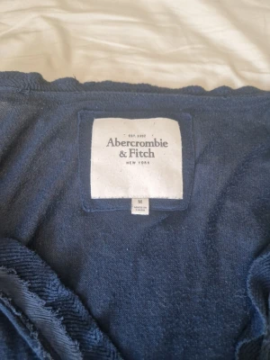 Mörkblå kofta från abercrombie & fitch - Snygg mörkblå kofta från Odd Molly med volangkant längs öppningen och två framfickor. Långärmad och i mjukt stickat material, perfekt för lager-på-lager-stil. Klassisk och feminin design.