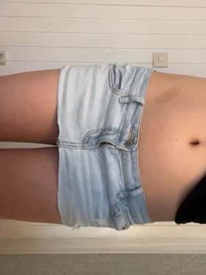 Ljusblå jeanskjol från Hollister  - Säljer en ljusblå jeanskjol från hollister med rå kant nertill . Midjemåttet rakt över : 38 cm och längden på kjolen: ca 21 cm. Hör av er vid några funderingar! Pris går att diskutera. OBS kjolen är väldigt kort.