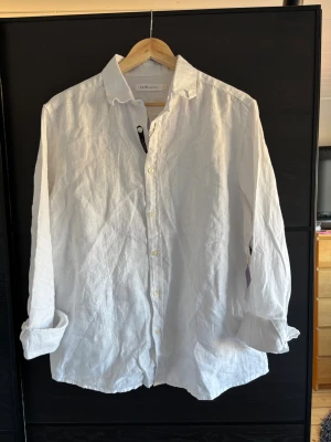 Vit linneskjorta - Klassisk vit skjorta i luftigt linne. Skjortan har lång ärm, knappar framtill och en avslappnad passform. Perfekt till sommaren och enkel att styla med både jeans och shorts. Hör gärna av dig om du vill ha fler bilder eller har några frågor