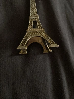 Eiffeltornet brosch i metall - Snygg brosch i form av Eiffeltornet, tillverkad i guldfärgad metall med detaljerad design. Perfekt accessoar för dig som gillar Paris eller vill ha något unikt på jackan eller väskan.