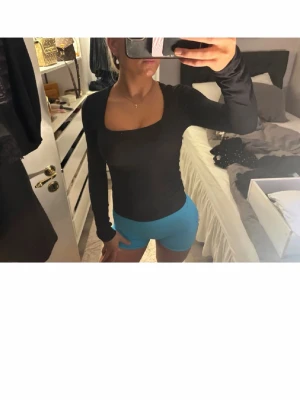 Svart långärmad topp med fyrkantig ringning - Säljer en svart långärmad topp med snygg fyrkantig ringning. Toppen har en tight passform och är perfekt att styla till både jeans och kjol. Materialet känns mjukt och stretchigt, vilket gör den bekväm att bära hela dagen.