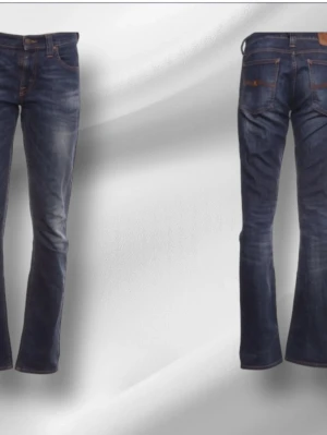 Blå jeans från Nudie Jeans Co - Säljer ett par klassiska blå jeans från Nudie Jeans Co med snygga slitningar och kontrastsömmar. Jeansen har fem fickor, normal midja och raka ben. Tillverkade i slitstarkt denim med cool tvättad look och detaljerade sömmar.