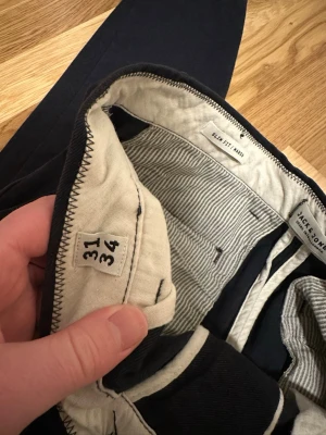 Mörkblå slim fit byxor Jack & Jones stl 31/34 - Byxor i fint begagnat skick bortsett från ett litet hål vid ena bakfickan. Slim fit 