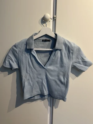 Ljusblå croppad topp - Säljer en ljusblå croppad polotopp från Zara. Perfekt til sommaren med ett par jeans till! 